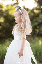 Load image into Gallery viewer, Girl in Sofia champagne lace flower girl dress with floral headpiece side view