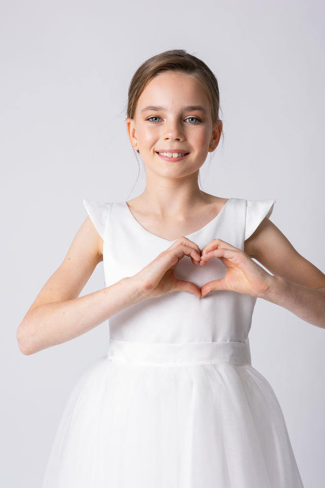Tween girl in modern formal dress with short sleeves forming a love heart with her hands